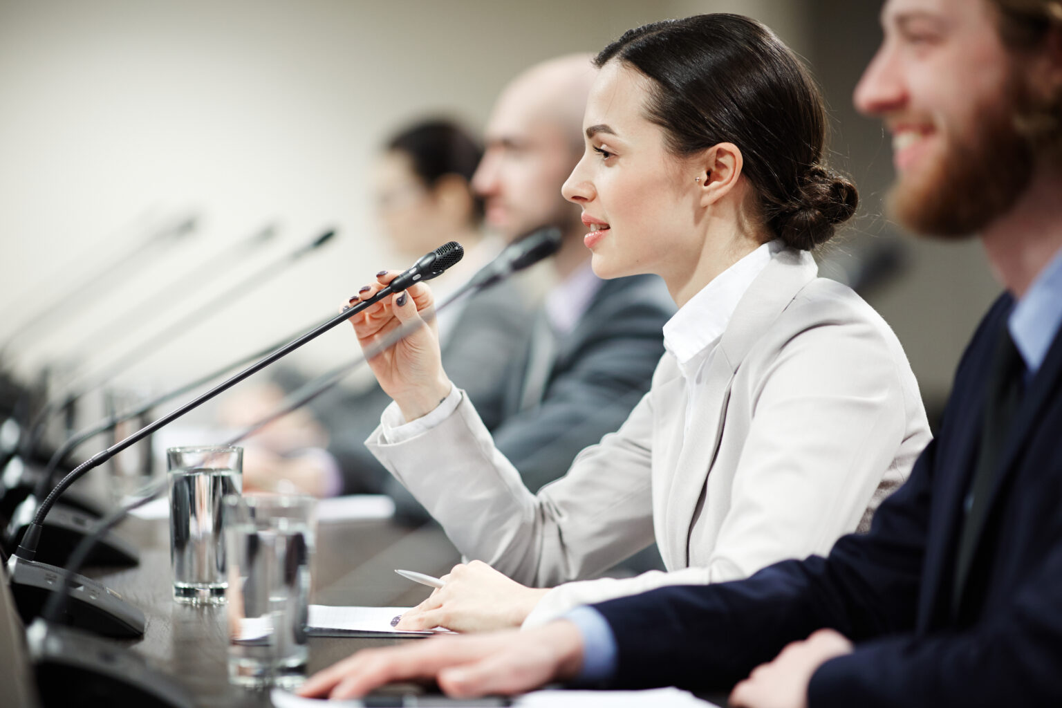 An elected official speaking into a microphone among other conference participants